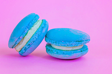 Sweet almond colorful unicorn blue macaron or macaroon dessert cake isolated on trendy pink pastel background. French sweet cookie. Minimal food bakery concept.