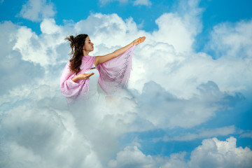 Young girl praying in the clouds
