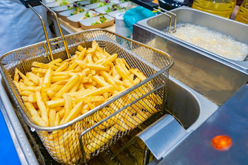 Cooking French fries. Potatoes are cooked in an industrial deep fryer. Frying products in hot oil. Fast food restaurant. Garnish. Industrial deep fryer closeup.