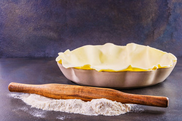 Préparation d'une pâte à tarte avant cuisson dans son moule à tarte avec de la farine sur le...