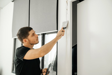 The male master makes repairs in the apartment, we close up cracks in the wall in the doorway. Home repair and household chores.