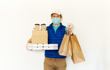 Delivery during quarantine. Courier in protective mask and gloves holding cardboard boxes reaching out hand with paper bags for takeaway food to clients. Takeout meal, online order, deivery to home