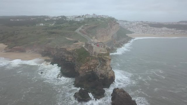 An iconic place on the Atlantic coast, the Mecca of big-wave surfing. View of Nazare's lighthouse in Zon North Canyon, place with the biggest waves in Europe, Nazare, Portugal