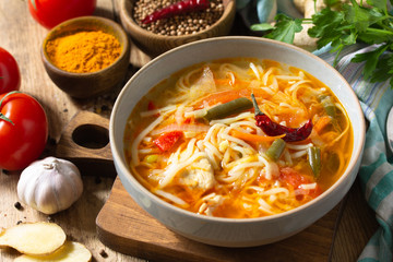 Tukpa soup of Indian cuisine. Hot noodle soup with chicken, ginger, cilantro and spices on a deyven wooden table.