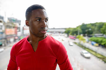 Face of young handsome African man thinking against view of the city