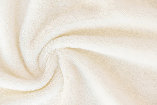 A soft cozy plaid made of white fabric with a pile lies in beautiful folds