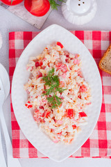 salad with crab sticks, tomatoes, cheese on a white dish, selective focus
