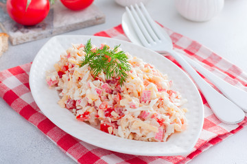 Homemade salad with crab sticks, tomatoes, cheese on a white dish, horizontal