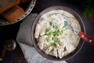 Stewed pork in sour cream in a ceramic bowl on a wooden table, selective focus