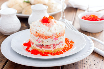 Holiday salad with red fish, shrimp, crab sticks, vegetables and red caviar, selective focus