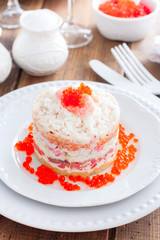 Holiday salad with red fish, shrimp, crab sticks, vegetables and red caviar, selective focus