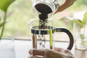 Pouring ground coffee into the French press coffee maker