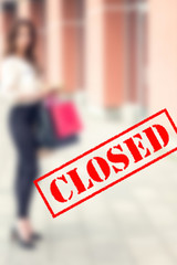 Word CLOSED on background of two young women in the shopping mall. Coronavirus quarantine. Closed shopping mall.