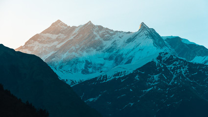 Dawn light hitting the snow covered peak of Annapurna One, the highest mountain of the Annapurna range, in the village of Kalopani in Nepal. - Powered by Adobe