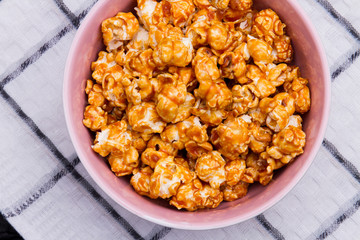 Close-up sweet popcorn in a bowl on white cotton napkin. Fried popcorn in ceramic plate.