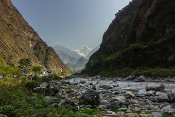 A distant, hazy view of the snow covered HImalayan peak of Nilgiri South from the banks of the Kali Gandaki river in the village of Tatopani in Nepal.