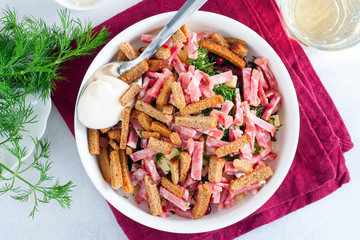 Salad with red beans, smoked sausage, cheese and crackers in a white bowl, selective focus