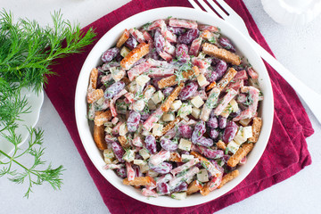 Salad with red beans, smoked sausage, cheese and crackers in a white bowl, selective focus