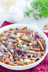 Salad with red beans, smoked sausage, cheese and crackers in a white bowl, selective focus