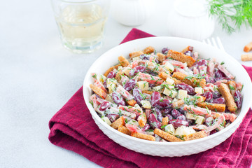 Salad with red beans, smoked sausage, cheese and crackers in a white bowl, horizontal, copy space