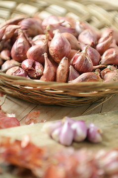 red onions, shallot in rattan basket and wooden background