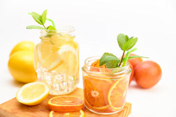 Pitcher and glass of homemade lemonade and orangeade with some mint leaves