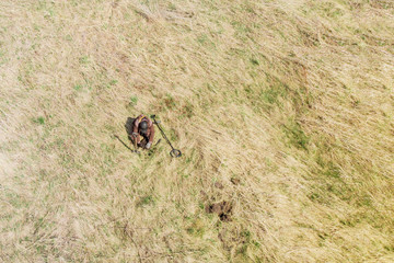 a man with a metal detector on an ancient settlement photographed from a drone