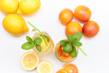 Pitcher and glass of homemade lemonade and orangeade with some mint leaves
