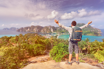 Travel man with photo backpack enjoy amazing view nature landscape island phi-phi from top of mountain at sunrise. Active lifestyle and Travel concept