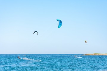 Kitesurfers with colorful kites having fun in Loutsa Greece on a sunny summer day, horizontal