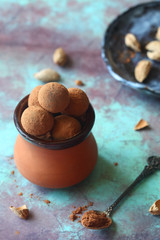 Homemade Chocolate truffles rolled in cocoa powder, in a little clay pot, on a vintage brown blue background.