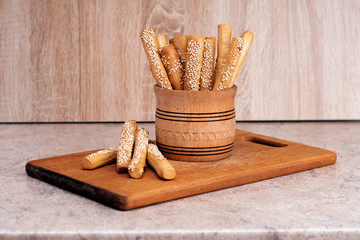 Crispy bread sticks with sesame seeds and bran bread on a wooden board.