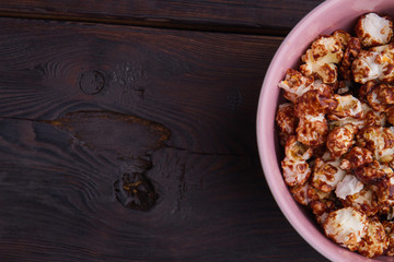 Half of bowl with chocolate popcorn on wooden background. Homemade chocolate popcorn. Concept of watching tv at home.