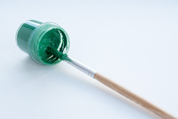 plastic jar with green paint and brush