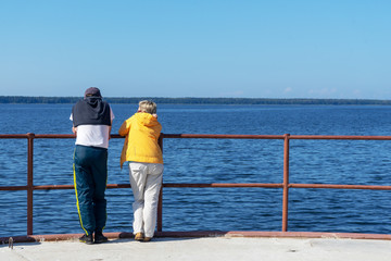 A man and a woman stand with their backs to the camera and look at the seascape.