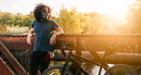 Man with surgical mask in the field with his bicycle