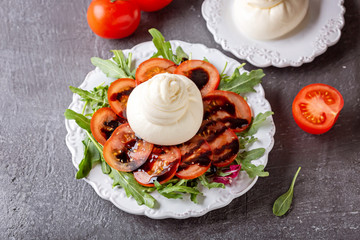 Salad with arugula, tomatoes and Italian burrata cheese. Top view