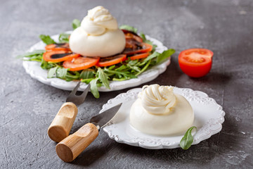 Fresh Italian cheese made from cow's milk - burrata on a white plate. Salad on a plate