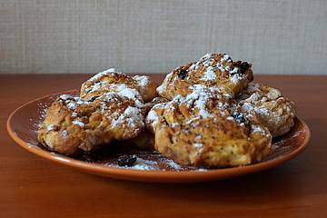  pastry with raisins, sprinkled with icing sugar in a plate on a wooden table,side view
