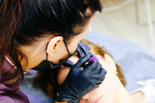 a woman is a master in the process of drawing a sketch of her eyebrows.