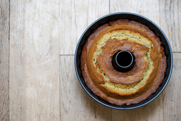 Fresh from the oven bundt cake in the tin, on the wooden background