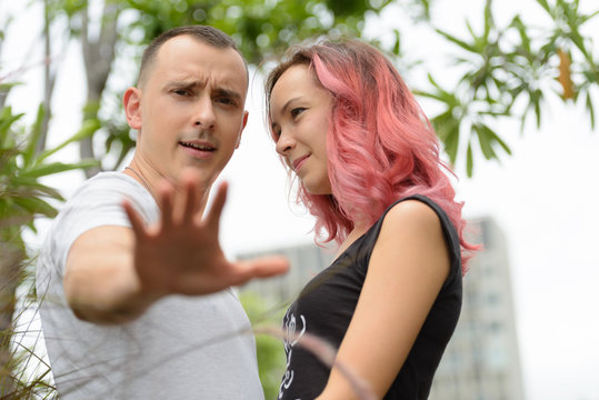Angry man with girlfriend showing stop gesture in the park