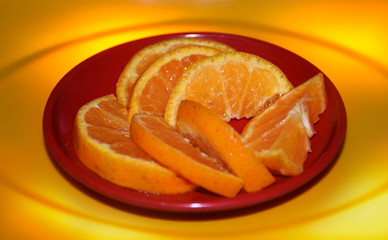 Closeup of Sliced Orange on a red plate isolated on a yellowish background