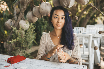 Woman is reading Tarot cards sitting at the table outdoors