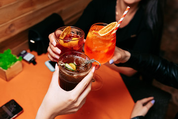 three girls clink glasses with summer alcoholic Cocktail.