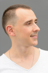 Fototapeta premium Face of happy handsome man thinking against gray wall