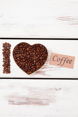 Grains roasted coffee in a shape of heart. I love coffee. White wood background.