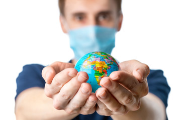 Close-up of a man's hands holding a small globe, with images Africa, a man in a medical mask out of focus, dressed in a blue t-shirt on a white isolated background. 2020, the global crisis.Coronavirus