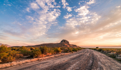 A dirt road leading into Lone Rock Basin in Utah. Taken as a colorful orange sunset filled the blue sky.