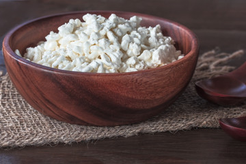 fresh cottage cheese in a wooden bowl on a sacking close-up. background with fermented milk products. cottage cheese close-up.